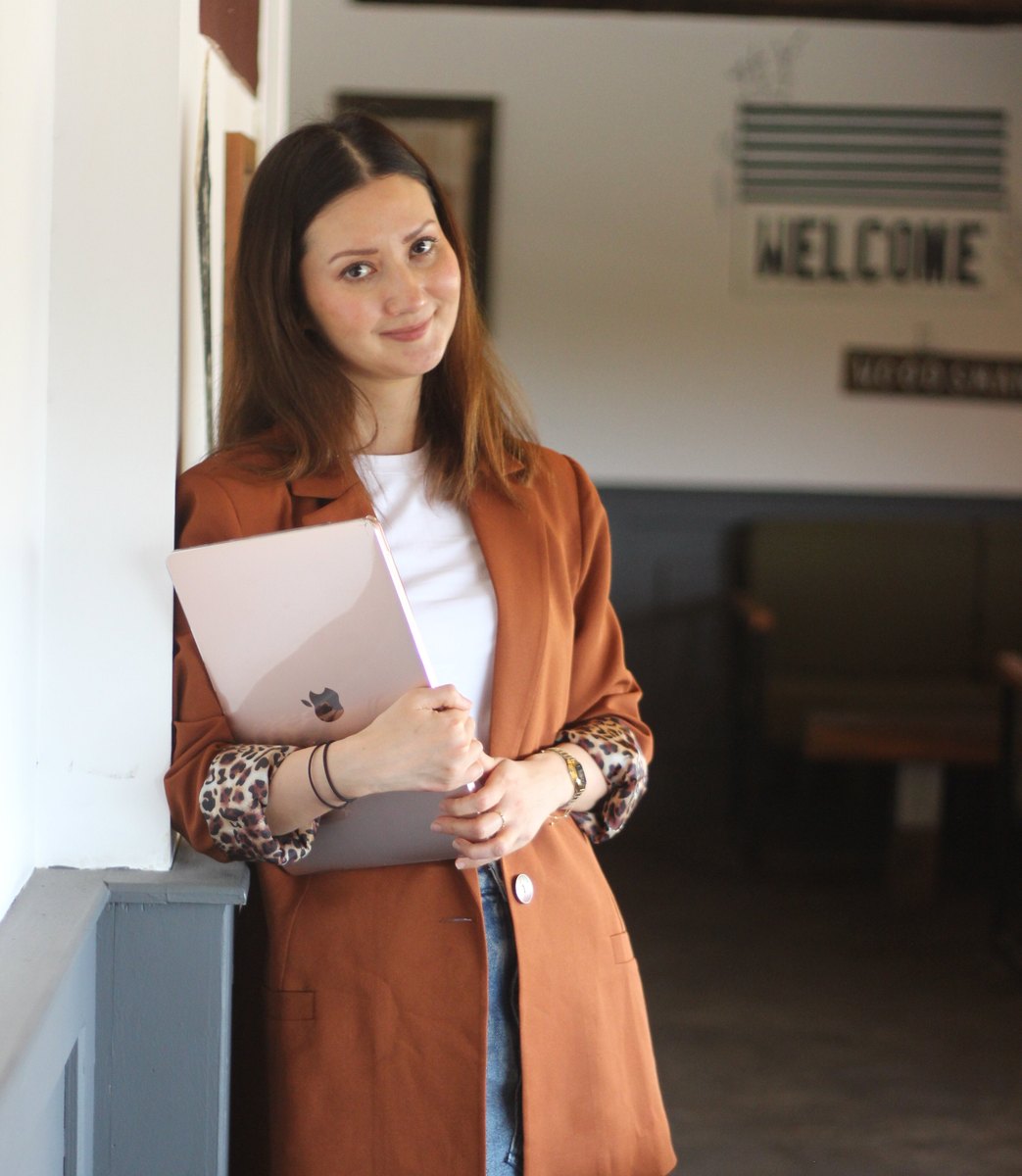 Dina, founder of Build Passive with Dina, holding her laptop